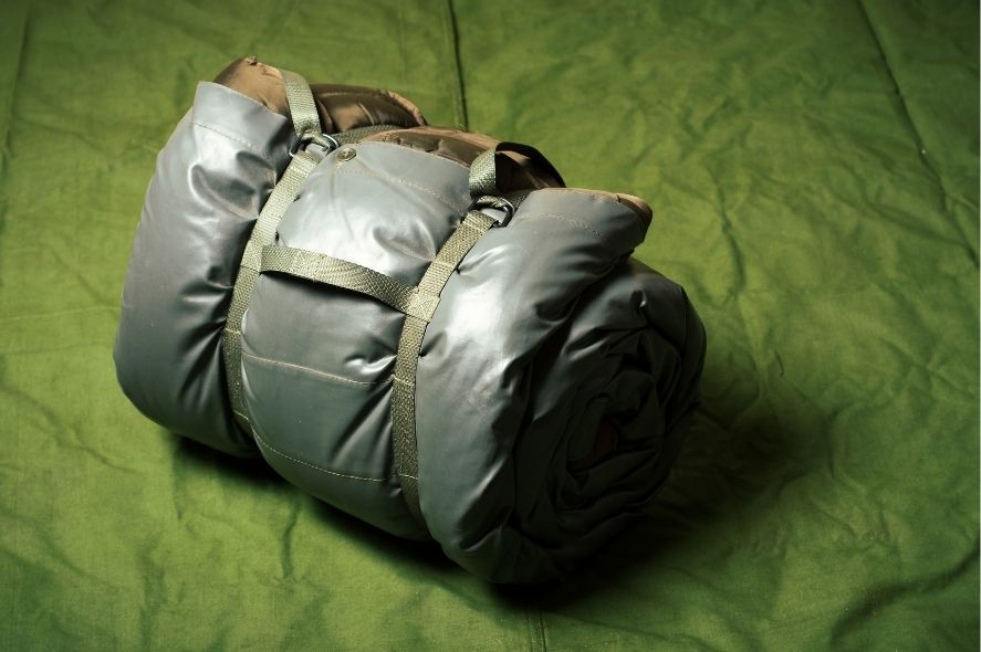 Στρατιωτικός κλειστός σάκος πάνω σε πράσινη κουβέρτα σε κρεβάτι στον στρατό.
